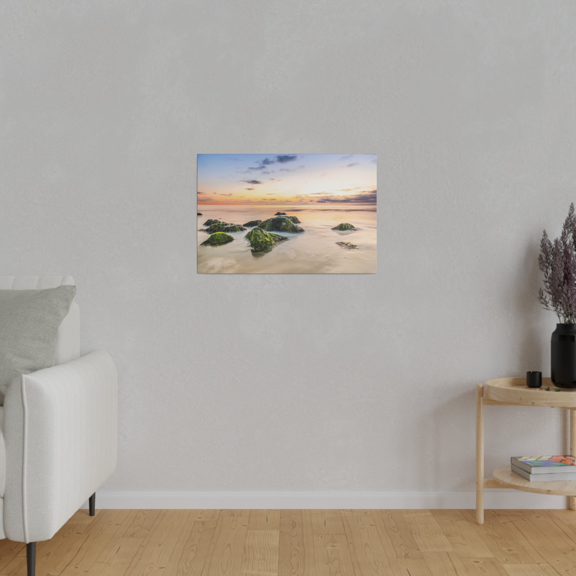 Small landscape photo of a sunset over rocky shoreline hangs on a light gray wall in a minimalist living room.