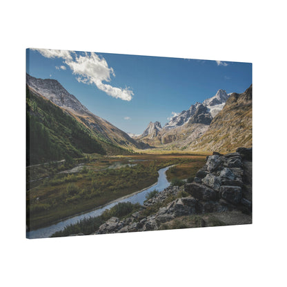 Printed canvas wall art showing a mountain valley with a winding river, green slopes, rocky foreground, and a blue sky.