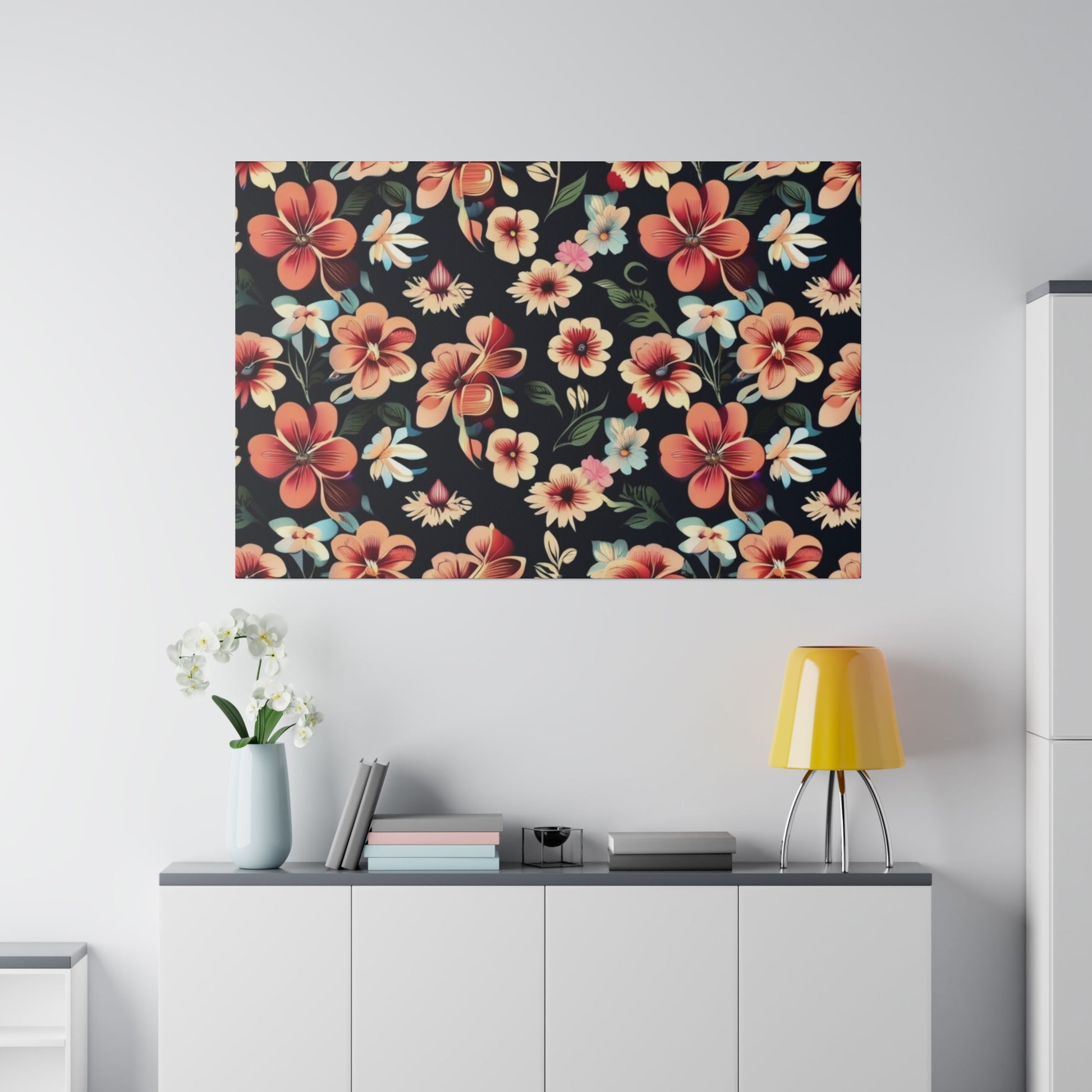 Large rectangular wall art with a black background and colorful hibiscus flowers above a white cabinet with books and a yellow lamp.