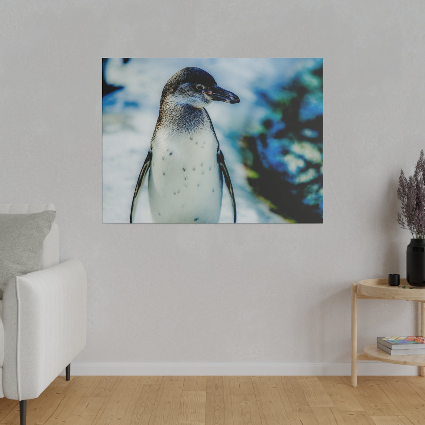 A solitary penguin in the snow, with a blurred background of blue and white. The photograph captures the penguin in a natural and peaceful moment.