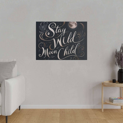 Dark blue canvas print with beige cursive text “Stay Wild Moon Child” and decorative swirls, hung on a light gray wall above a sofa.