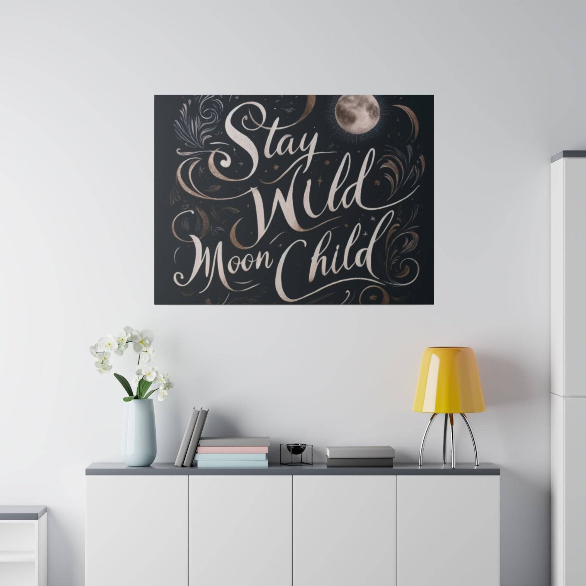 Framed wall art with the words 'Stay Wild Moon Child' in white script on a dark background with decorative swirls.