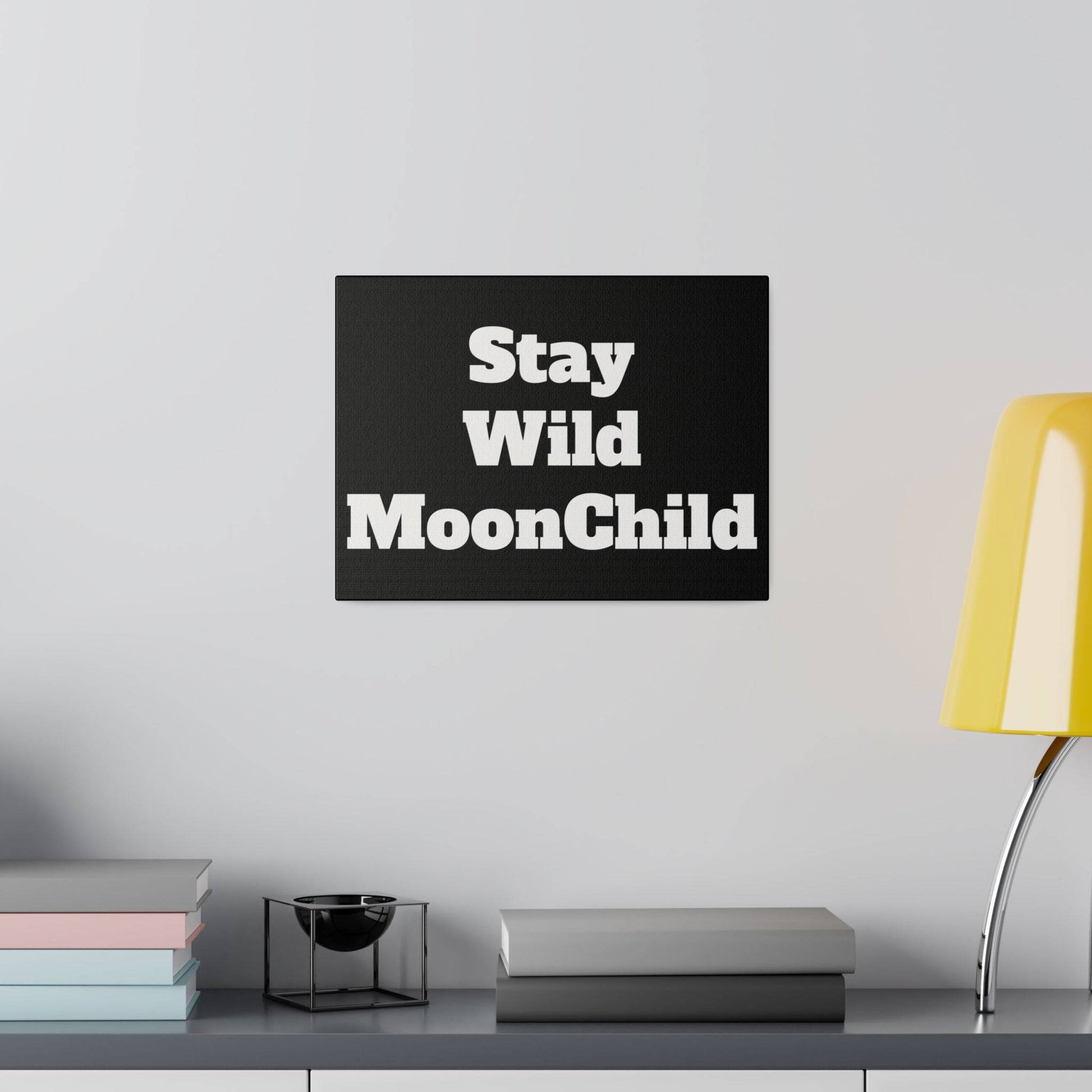 Black rectangular wall plaque with bold white text Stay Wild MoonChild mounted above a shelf.
