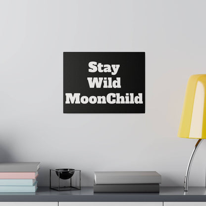 Black rectangular wall plaque with bold white text Stay Wild MoonChild mounted above a shelf.