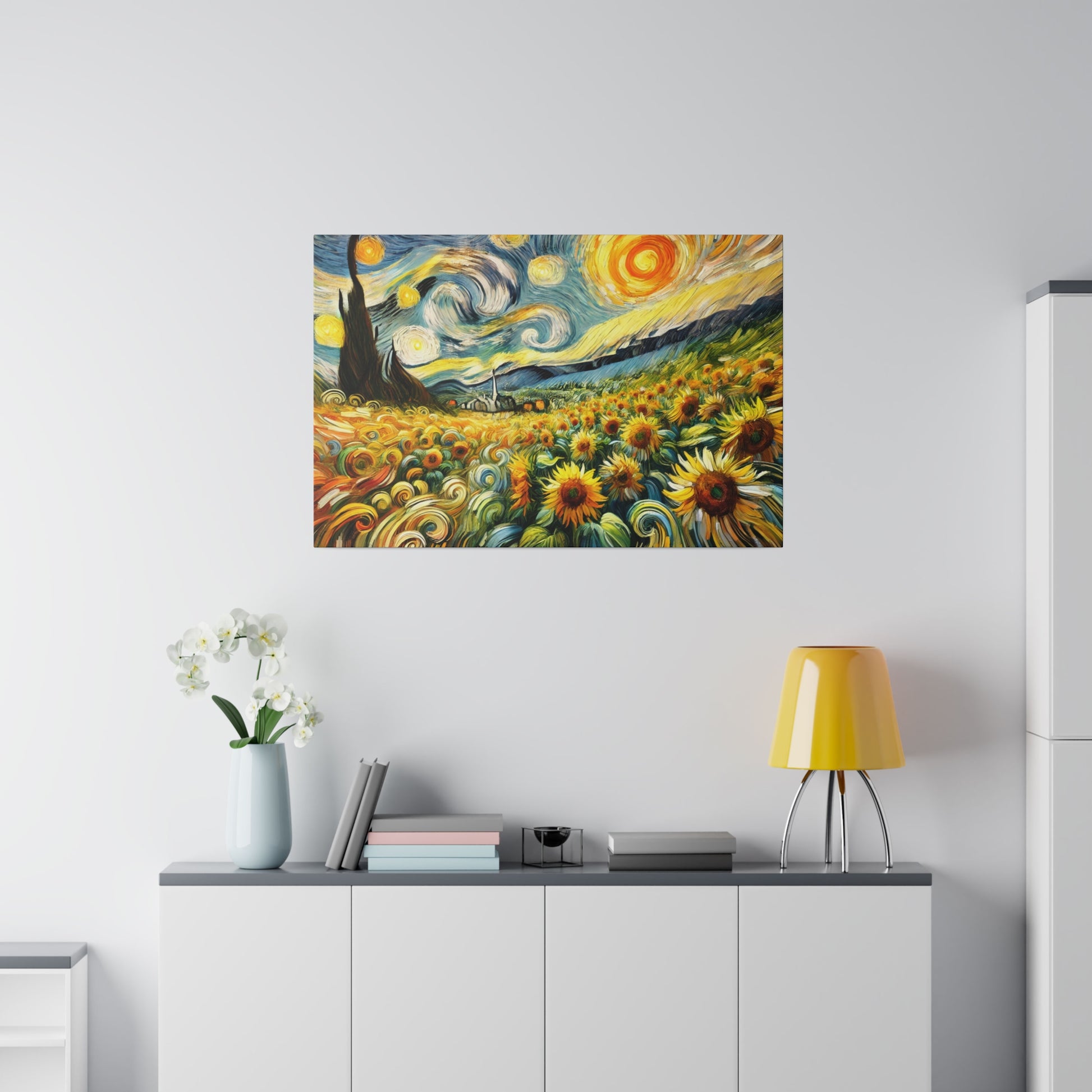 Colorful painting of a sunflower field with swirling sky hangs above a white sideboard with a yellow lamp and vase of white flowers.