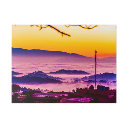 Sunrise over a foggy valley with purple hills, orange sky, and a tall cell tower near small buildings.