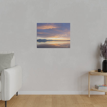 Framed landscape print of a sunset over a calm lake with distant mountains and a colorful orange-purple sky.