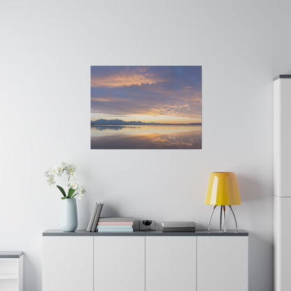 Framed landscape canvas of a sunset over a calm lake with distant mountains, hung above a white cabinet.