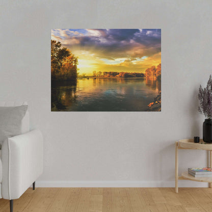 Square photo of a sunset over a calm river, with orange trees along both banks and a golden sky reflecting on the water.