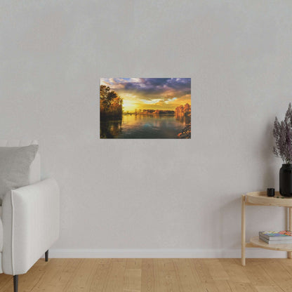 Rectangular wall art showing a sunset over a calm river with trees along the banks and warm orange, yellow, and blue reflections.