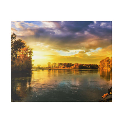 Calm river at sunset with golden sky, orange-hued trees along the bank and gently rippling water.
