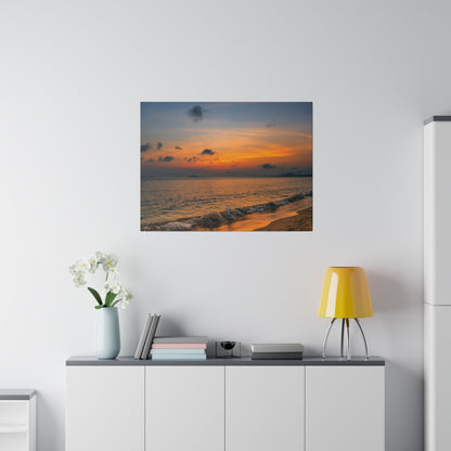 Square canvas print of a sunset over the ocean with an orange sky, dark clouds, and waves along the sandy shore.