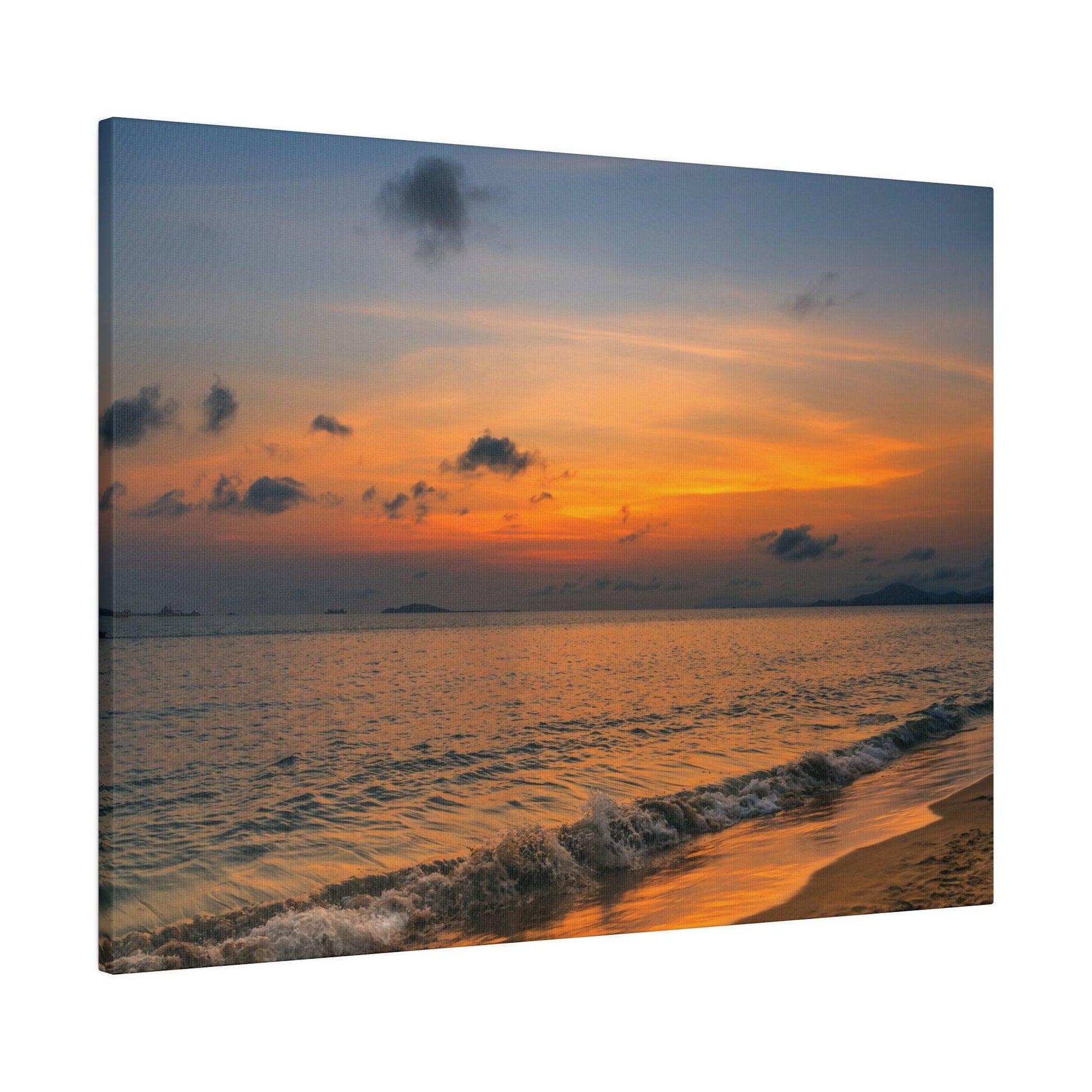 Beach scene at sunset: orange and blue sky over calm ocean with small waves washing onto the sandy shore.