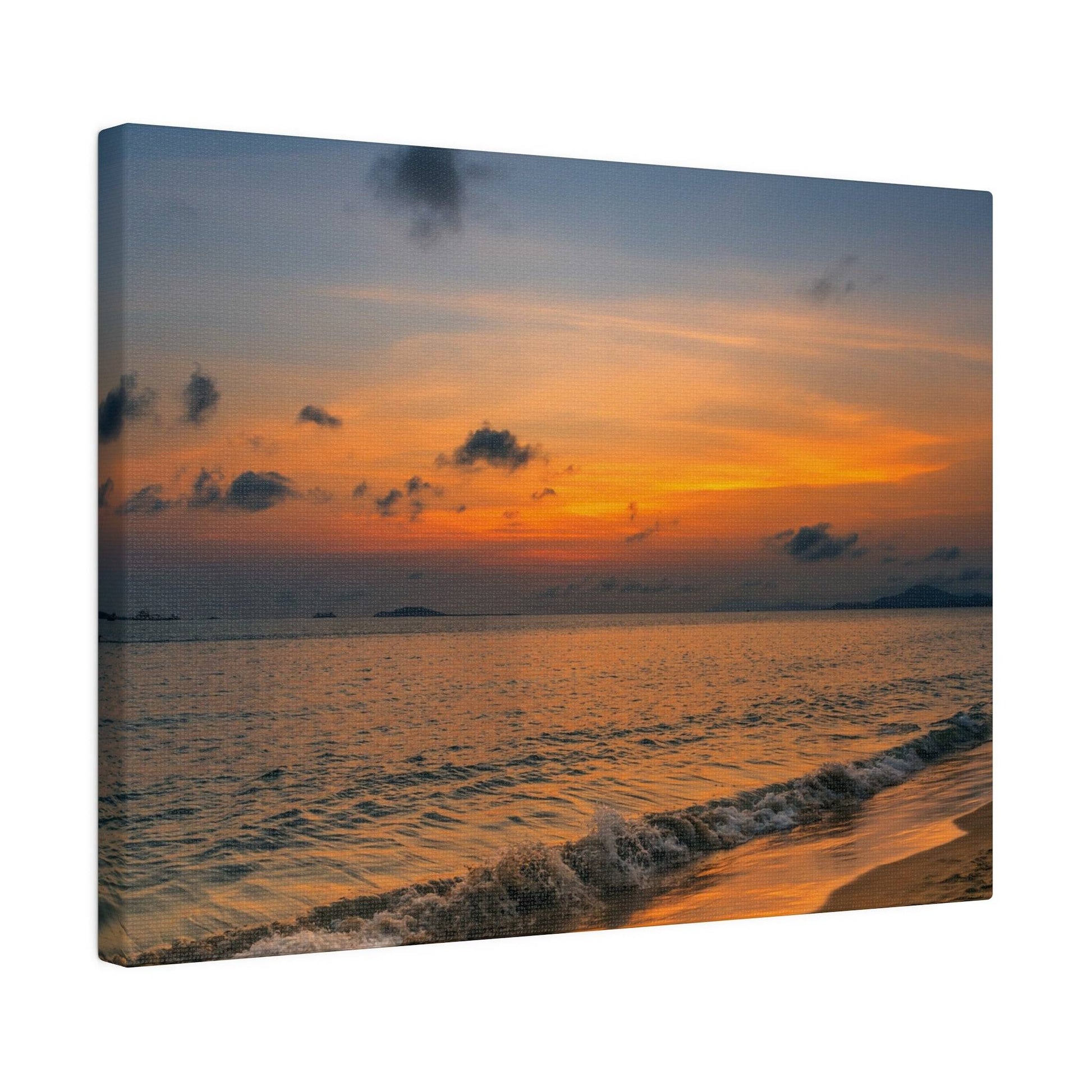 A canvas print of an orange sunset over a calm sea, with gentle waves washing onto a sandy shore.