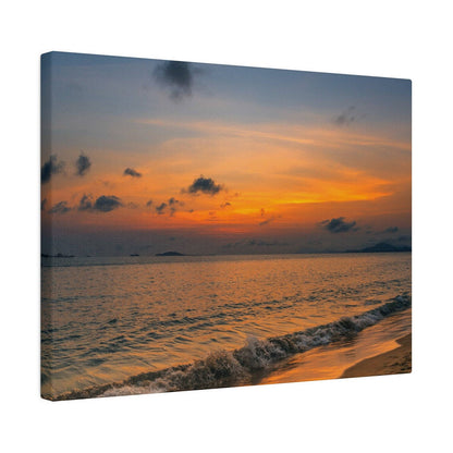A canvas print of an orange sunset over a calm sea, with gentle waves washing onto a sandy shore.