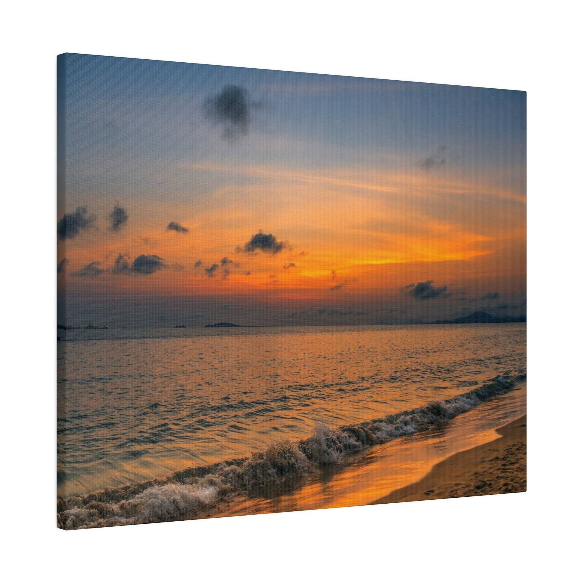 A sunset over the ocean with an orange and pink sky, distant islands, and gentle waves washing onto a sandy shore.