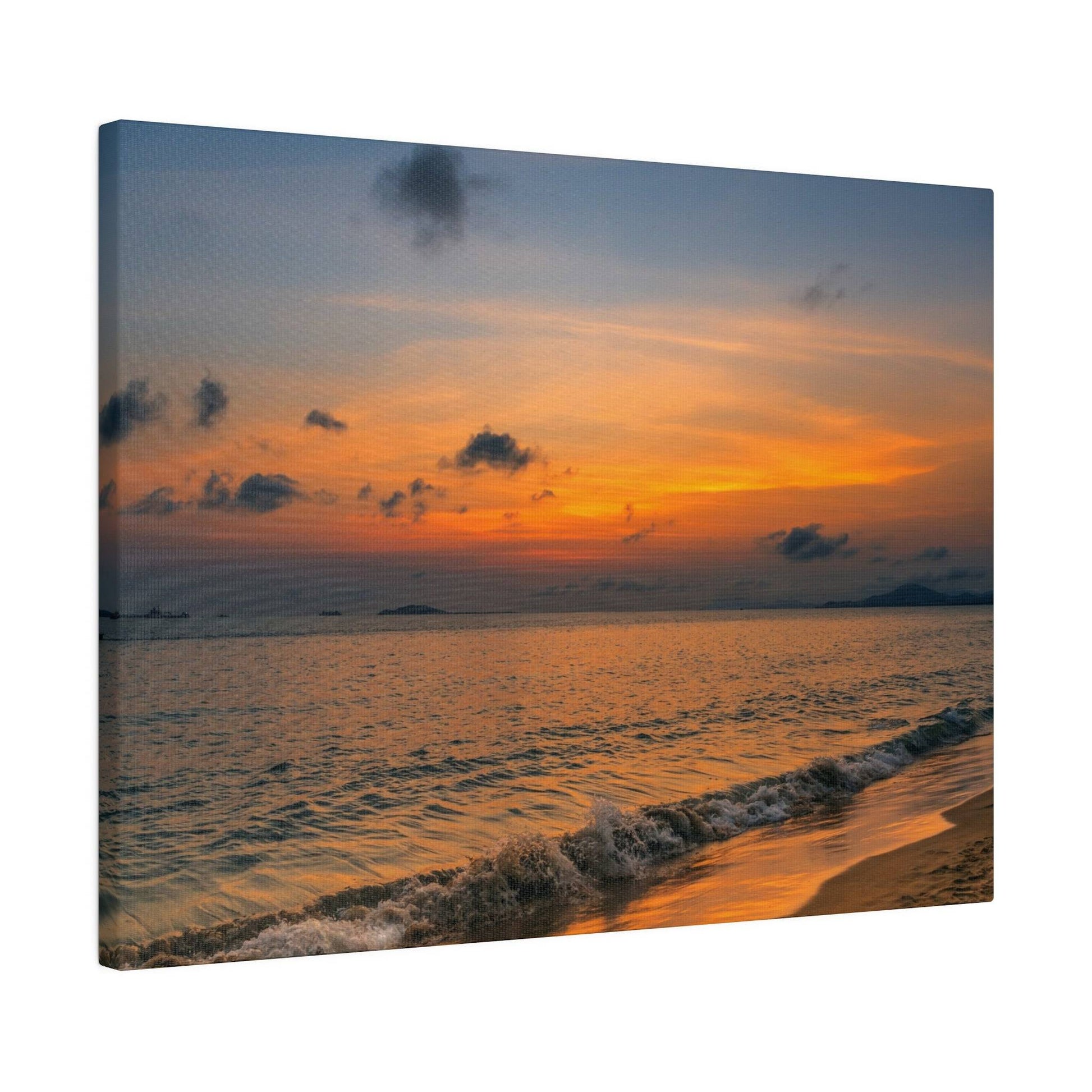 Orange sunset over a calm sea with small waves washing onto a sandy beach.