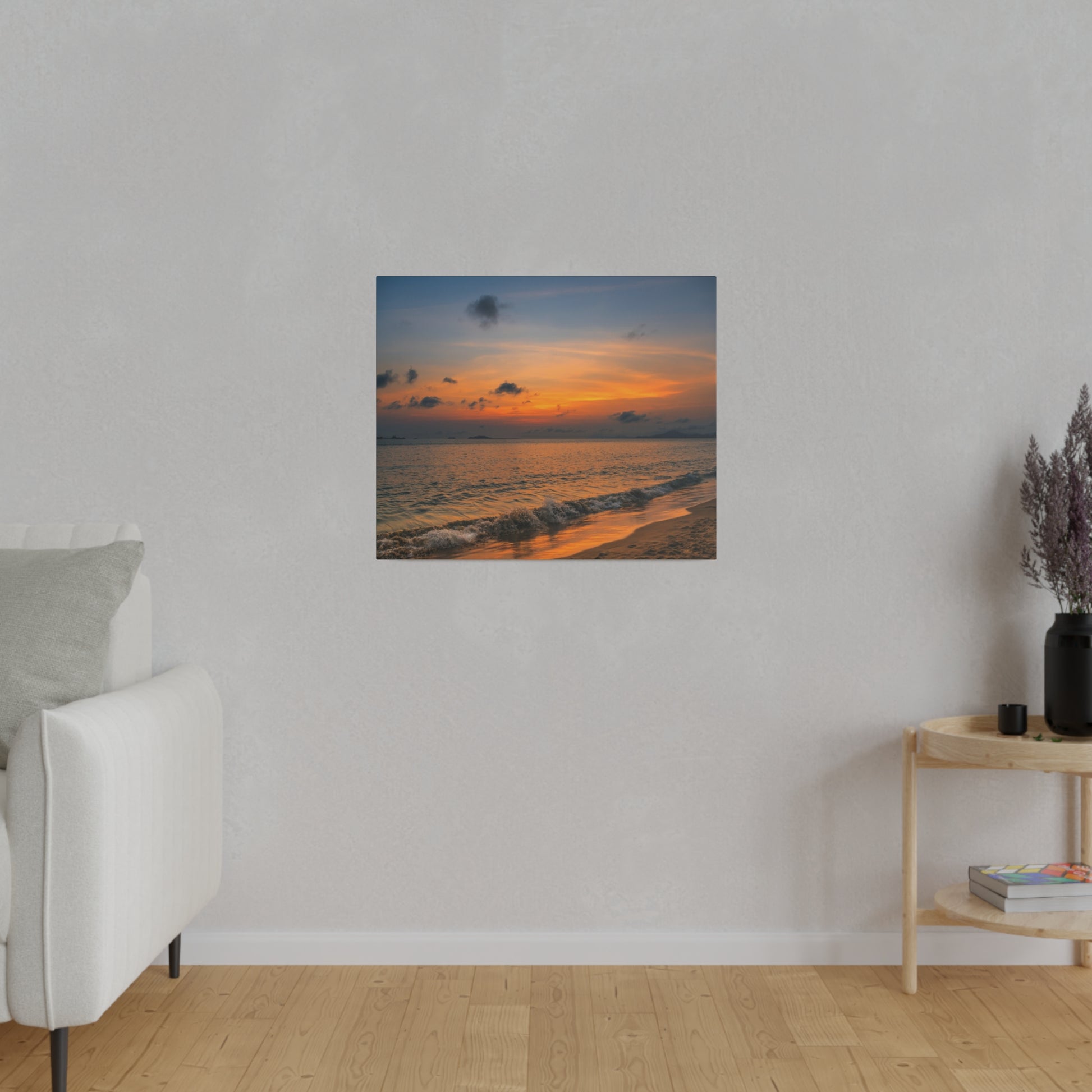A coastal sunset painting on a gray wall above a light-colored couch in a minimalist living room.