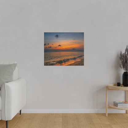 A coastal sunset painting on a gray wall above a light-colored couch in a minimalist living room.