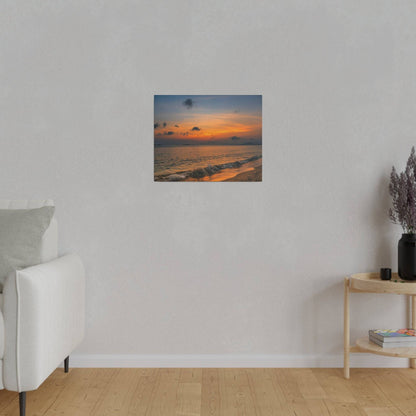 Small square painting of a sunset on a beach hangs on a light gray wall above a white sofa.