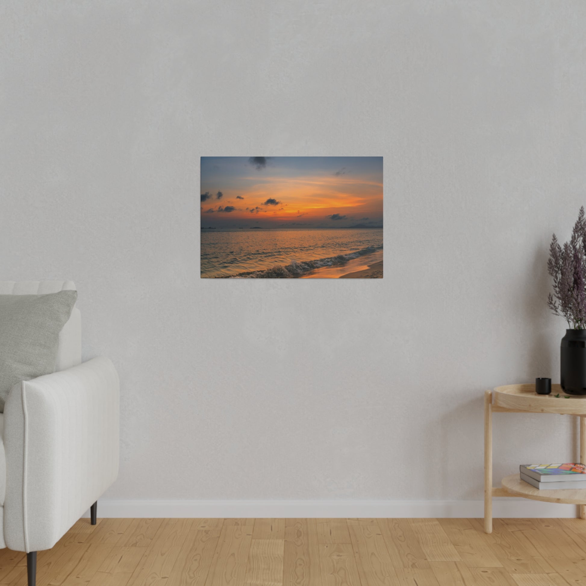 A small framed photo of a sunset over the ocean hangs on a light gray wall in a minimalist living room.