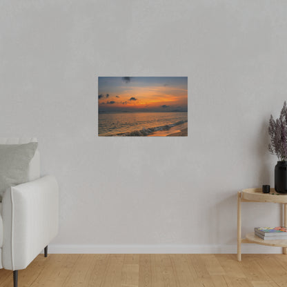 A small framed photo of a sunset over the ocean hangs on a light gray wall in a minimalist living room.