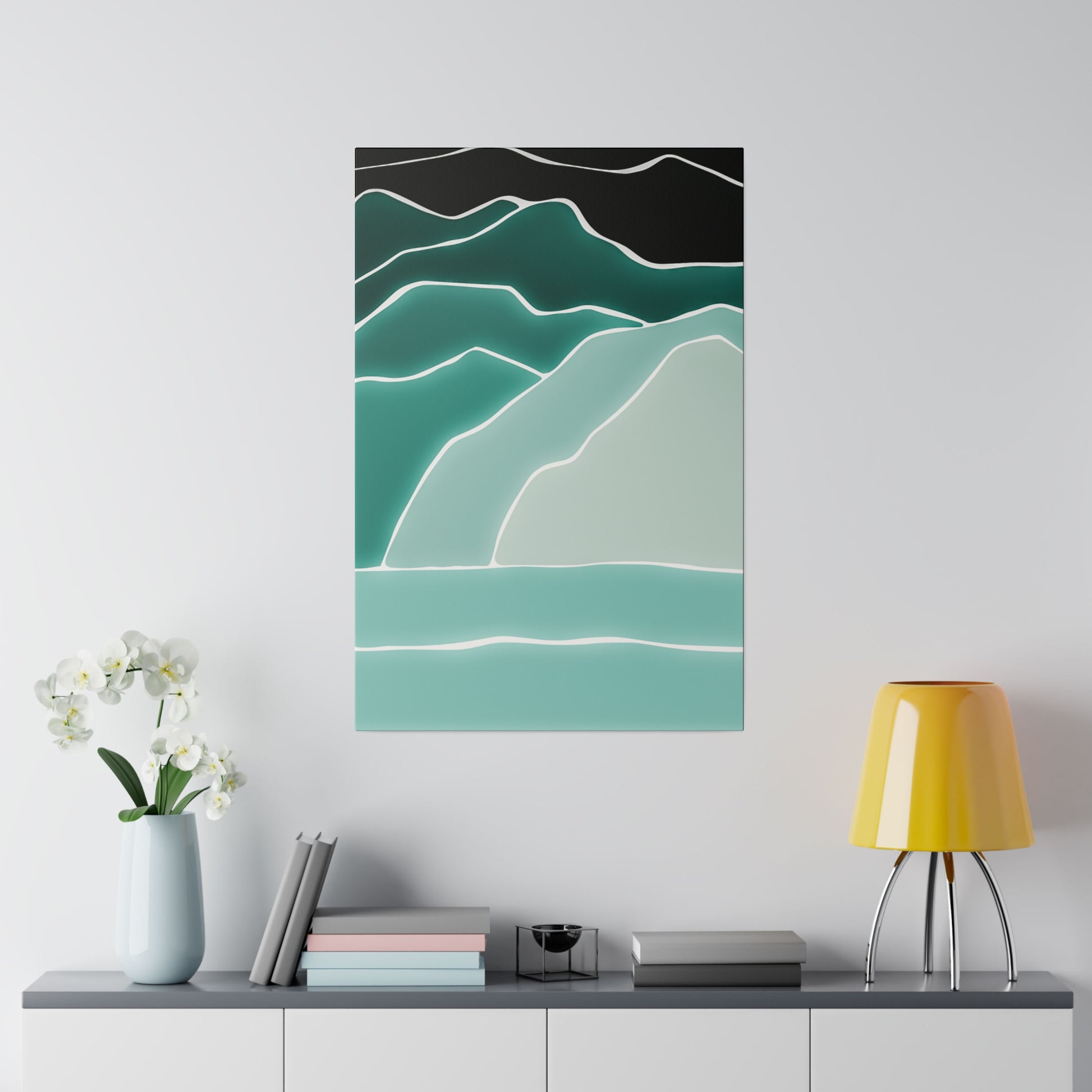 Vertical abstract wall art with layered teal mountains outlined in white against a black sky, hung above a console with a yellow lamp.