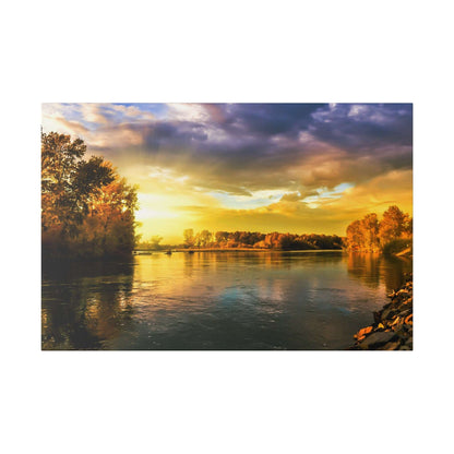 River at sunset with calm water, yellow-orange sky, and trees with autumn colors along both banks.