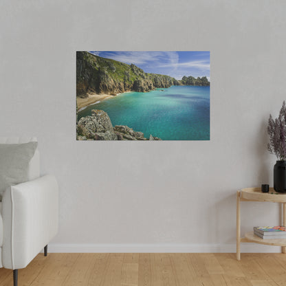 Framed coastal photo of turquoise sea, rocky cliffs, and sandy cove along a sunny shoreline.