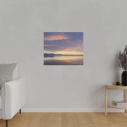 Framed landscape photo of a sunset over a calm lake with distant mountains, hung on a light gray wall.