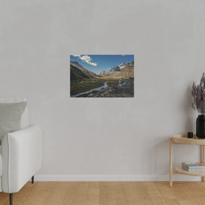Landscape photo of a mountain valley with a winding river, rocky foreground, blue sky and clouds.
