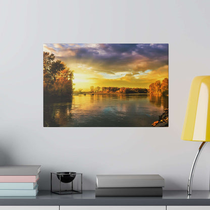 Landscape photo of a river at sunset, with orange-yellow sky, calm water, and trees along the banks.