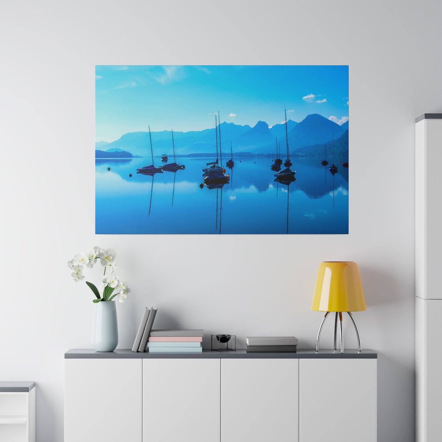 Tranquil sailing on a calm lake with sailboats anchored in the still water. The blue hues and mountain backdrop create a serene and peaceful atmosphere.