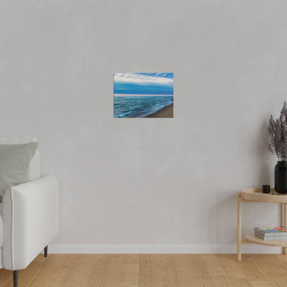 Small square painting of a blue ocean shoreline hangs on a light gray wall in a minimalist living room.