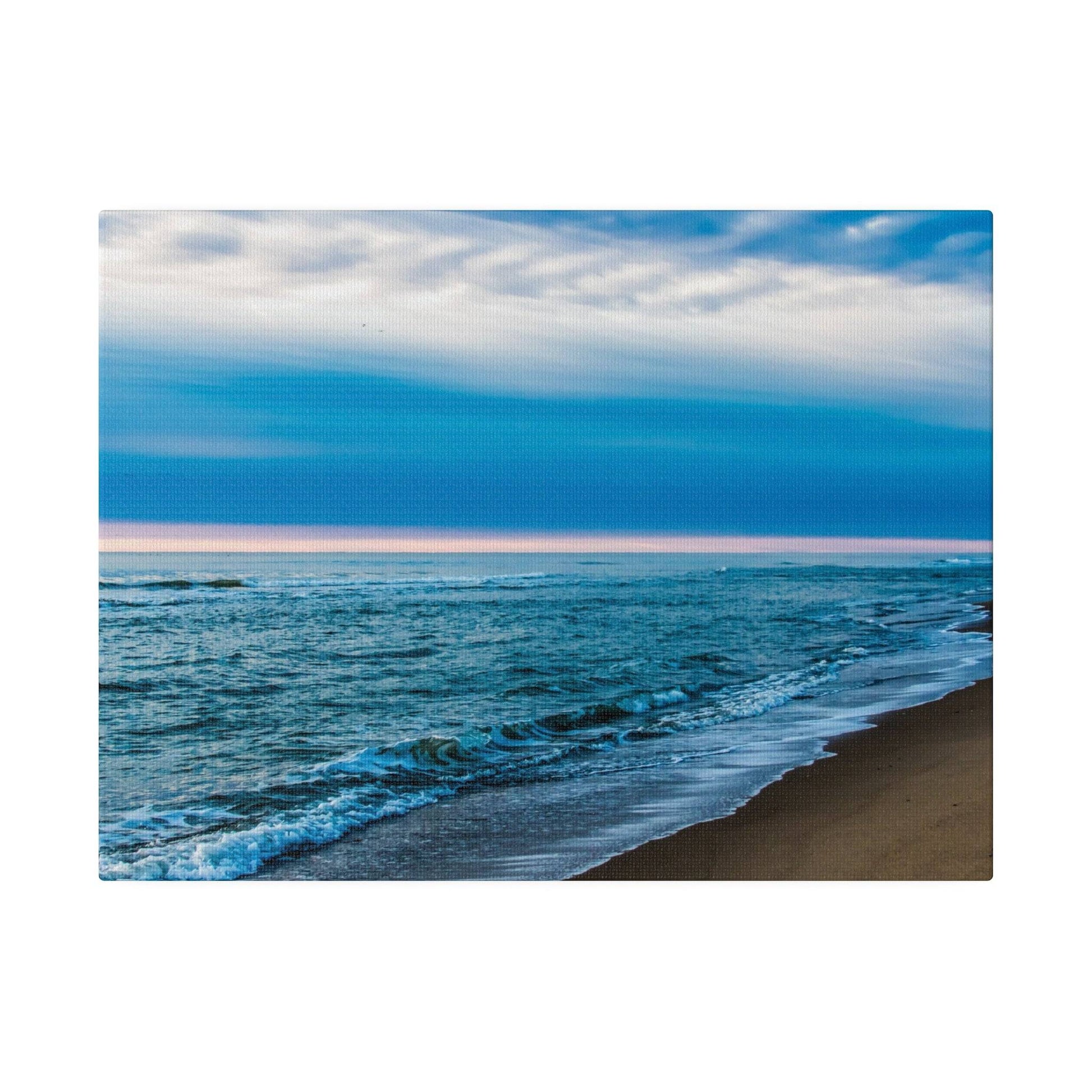 A beach scene with blue ocean waves washing onto a sandy shoreline under a cloudy sky.