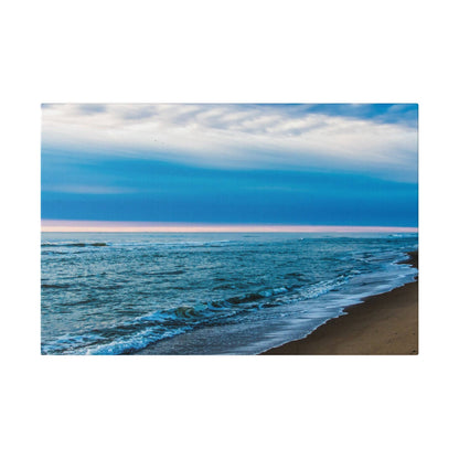 Beach scene with blue ocean waves washing onto a sandy shoreline under a cloudy sky.