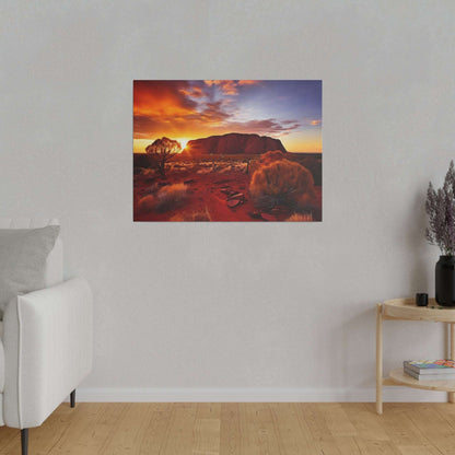 Uluru sunset canvas print showing the rock formation against an orange sky with desert shrubs in the foreground.