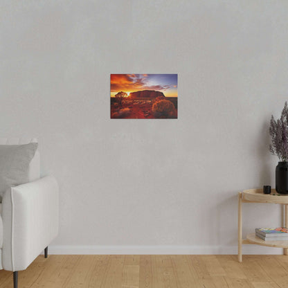 Small canvas print of Uluru at sunset with an orange sky, mounted on a light gray wall in a living room.