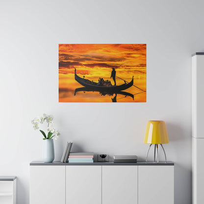 Orange sunset sky with a black gondola carrying passengers on calm water, hung on a white wall.