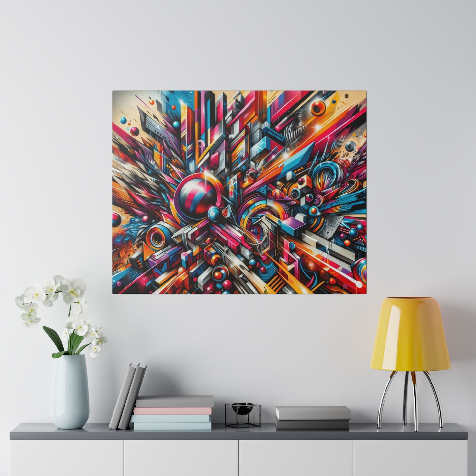 Abstract, geometric wall art with bright, multicolored shapes above a white console featuring a pale blue vase and a yellow lamp.