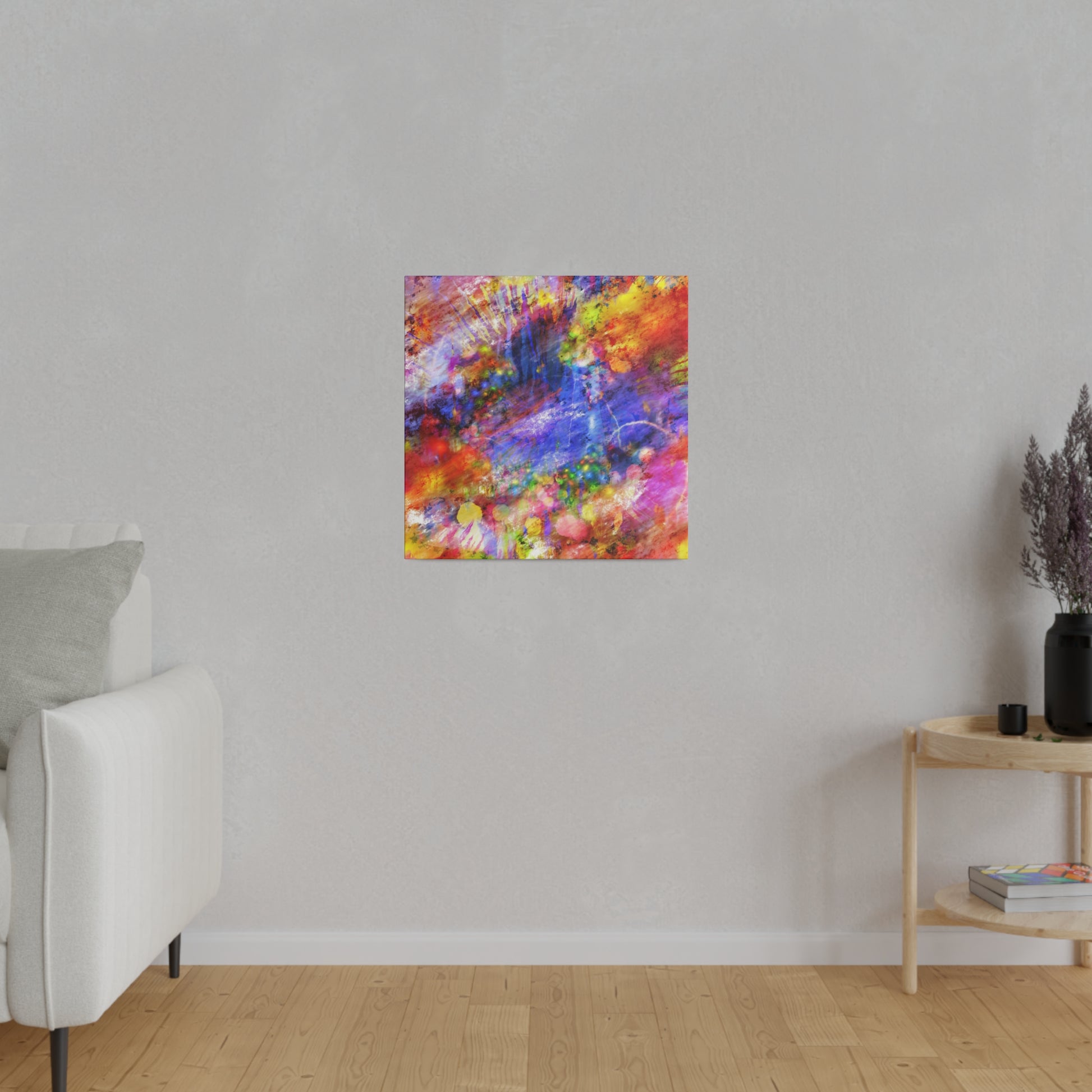 Abstract multicolor square painting with red, blue, yellow splashes hangs on a light gray wall in a minimalist living room.