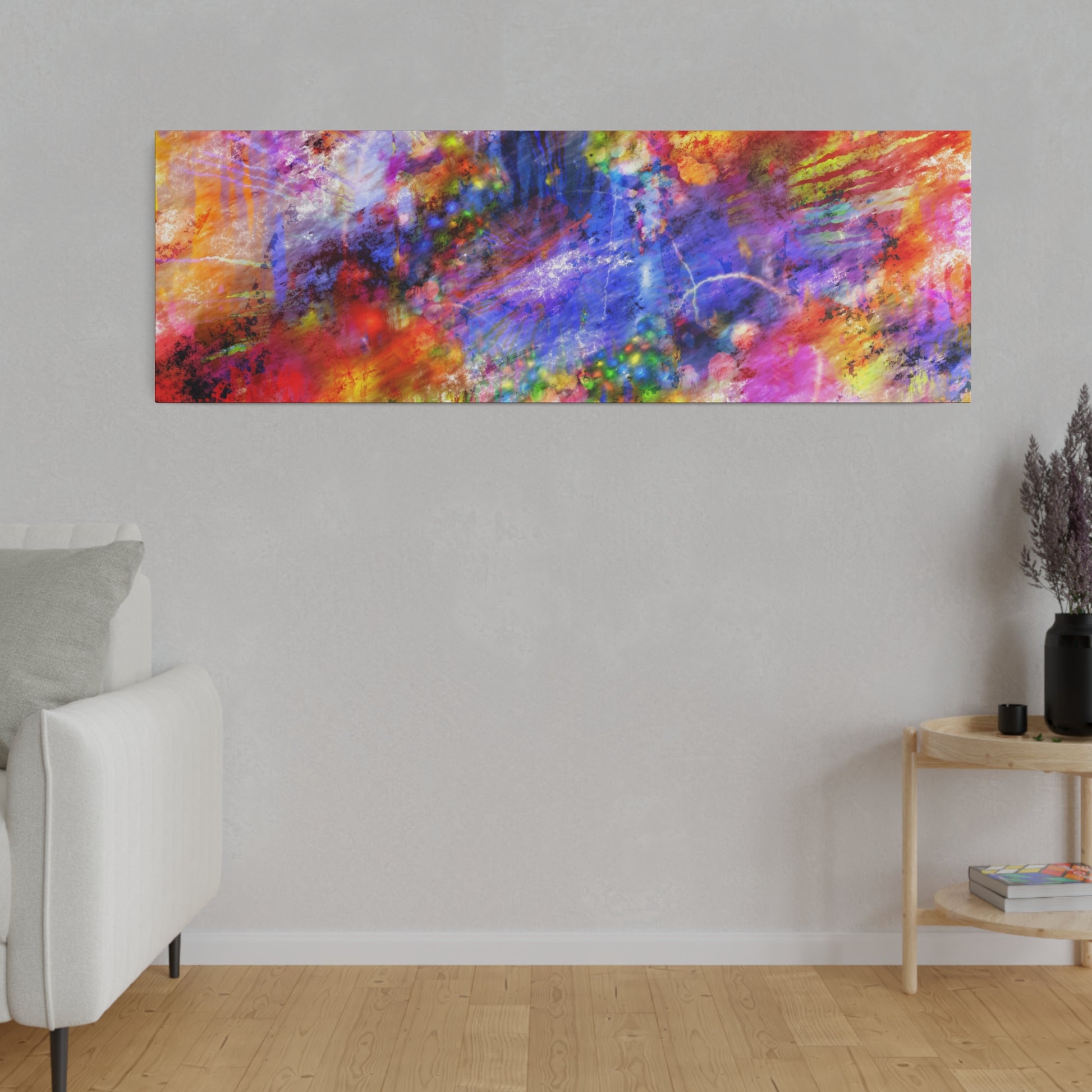 Rectangular abstract painting with vivid red, blue, yellow, and purple splashes hanging on a light gray wall above a white sofa.