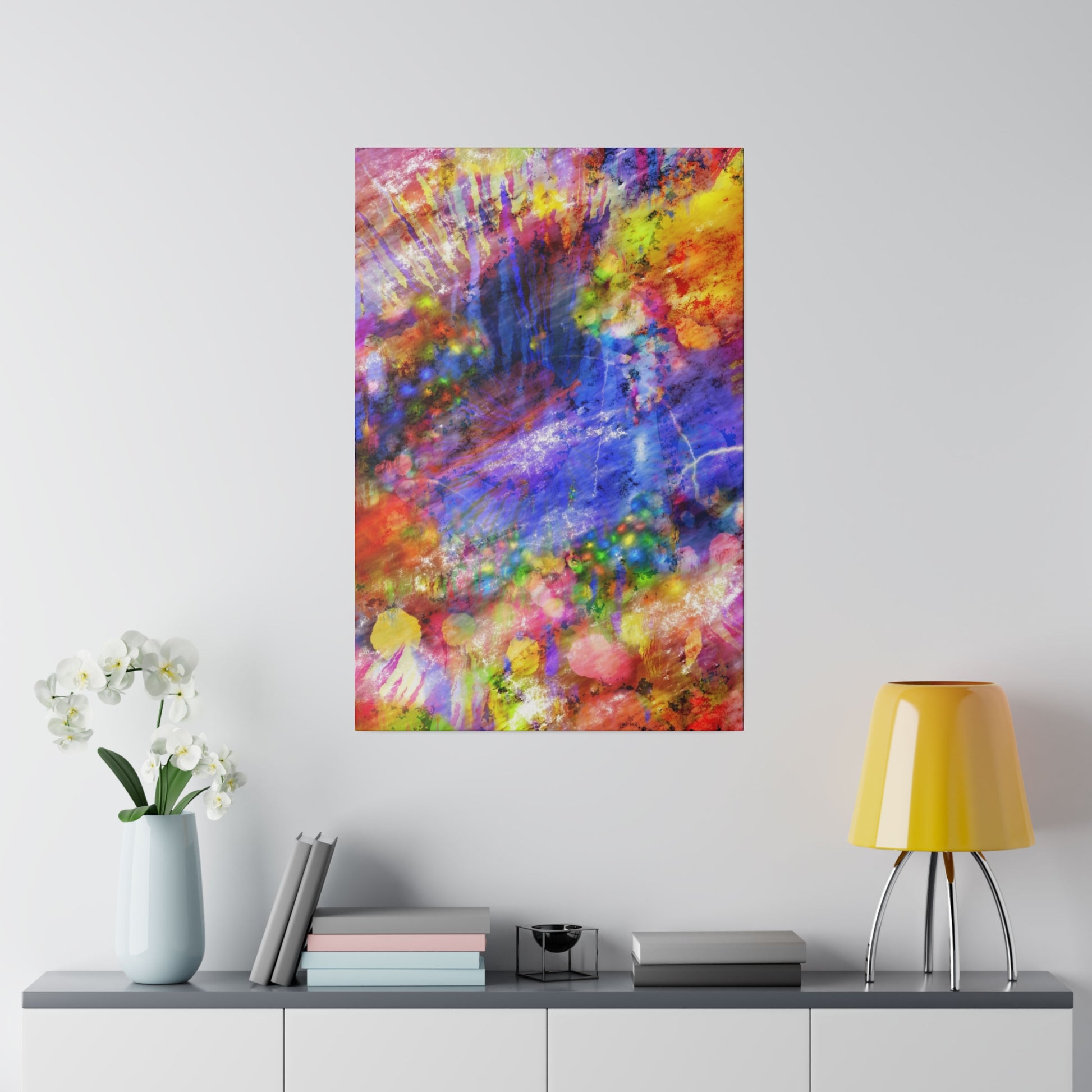 Abstract colorful painting with red, blue, yellow, and purple splashes hanging on a white wall above a gray console.