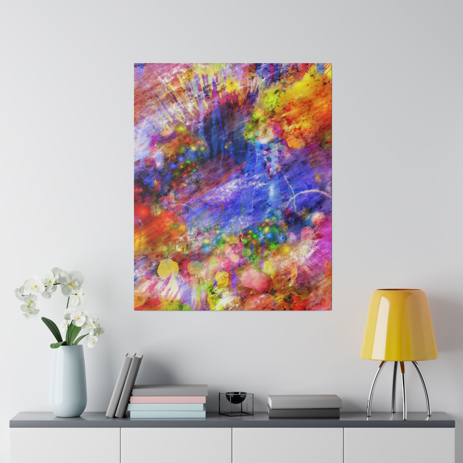 Abstract multicolored painting with vibrant blues, pinks, yellows, and greens hanging above a gray cabinet.