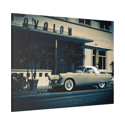Vintage pale convertible with a white hardtop parked in front of a beige building with an "AVALON" sign.