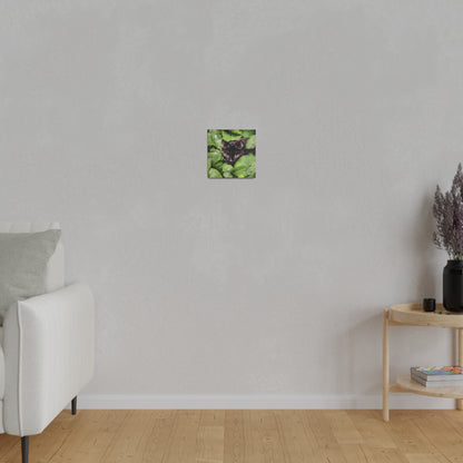 Small square wall art featuring a black cat's face surrounded by green leaves.