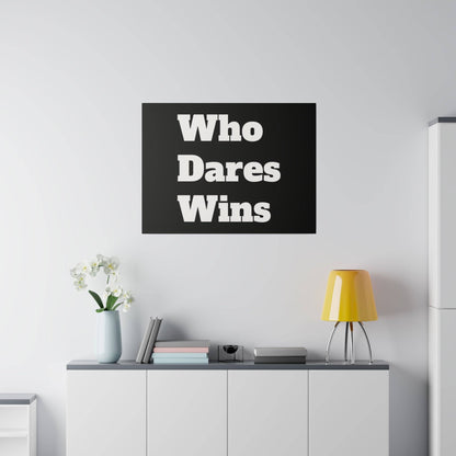 Black rectangular wall art with bold white text "Who Dares Wins" above a white cabinet, beside a vase of white flowers and a yellow lamp.