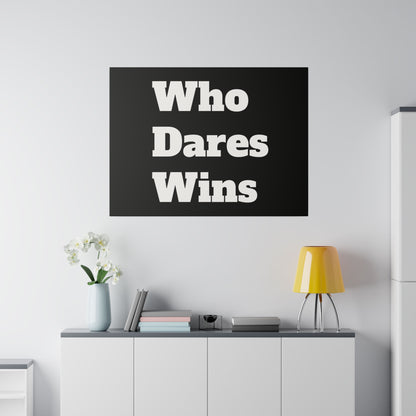 Black wall poster with white bold text Who Dares Wins mounted above a white cabinet with a yellow lamp and vase of white flowers.