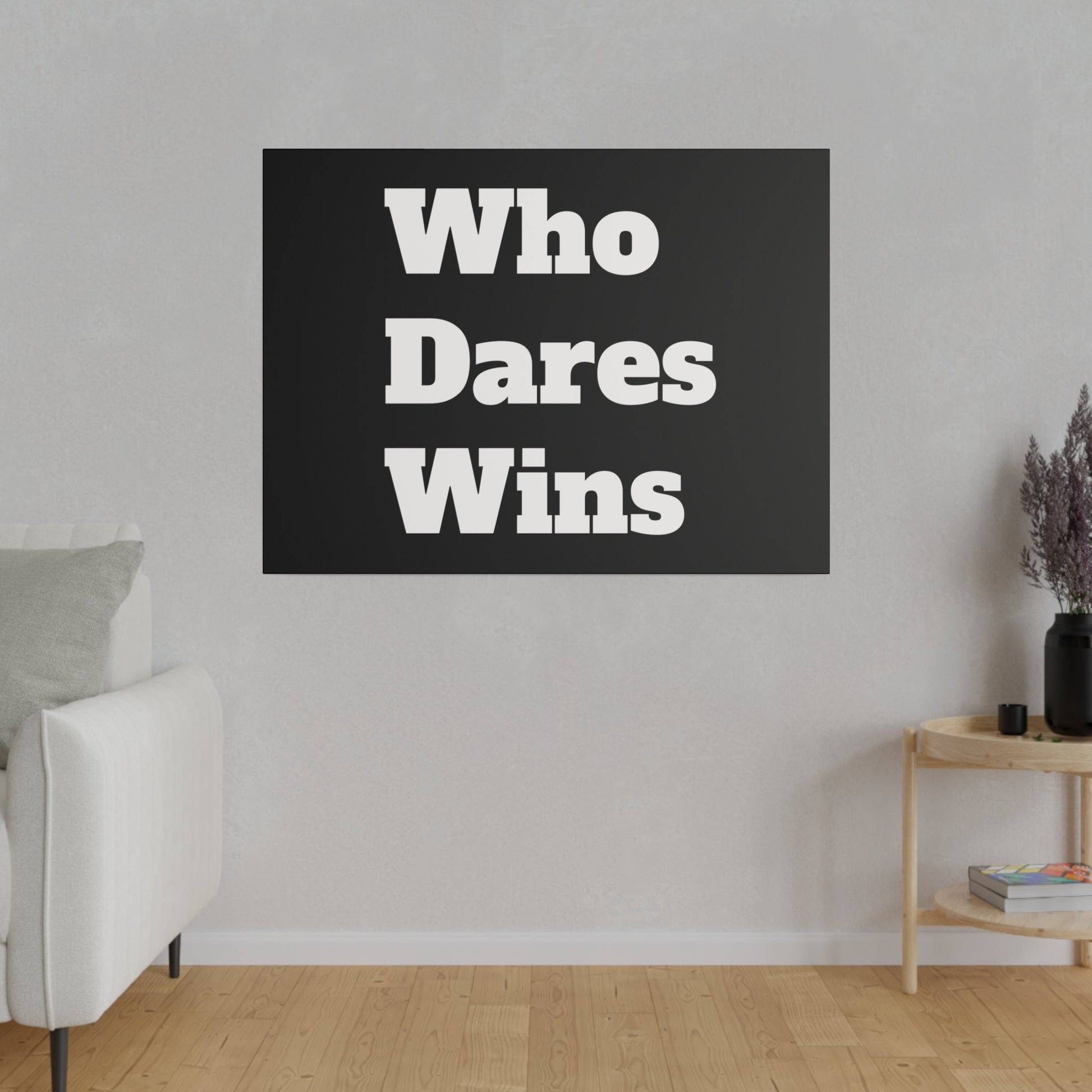 Black square poster on a light gray wall reads "Who Dares Wins" in bold white type, mounted above a white sofa.