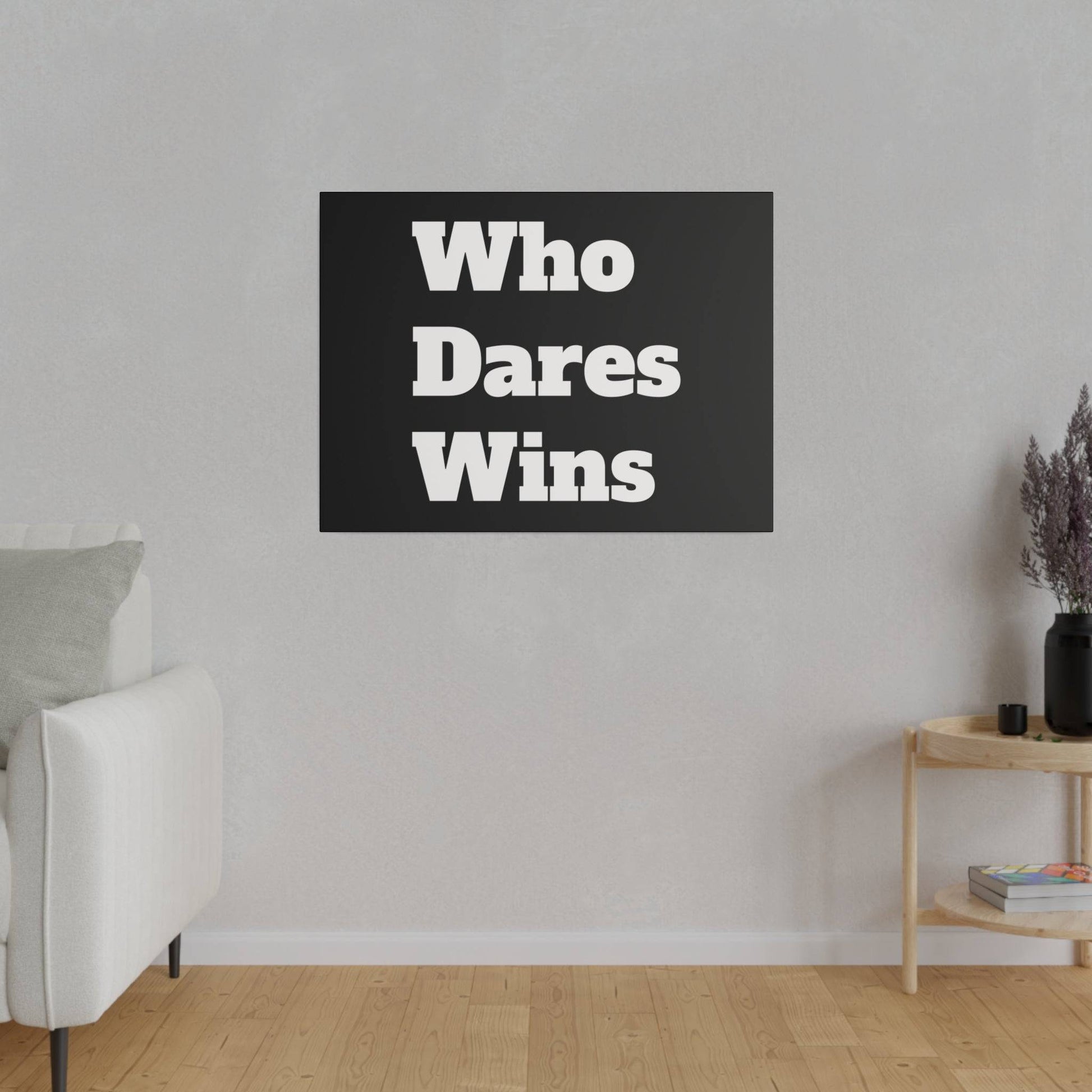 Black rectangular wall art with bold white text "Who Dares Wins" mounted above a light gray sofa in a minimalist living room.